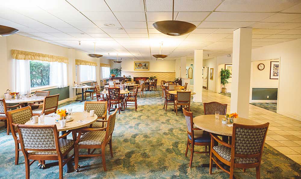 A spacious dining area with neatly arranged tables and chairs, featuring warm indoor lighting.