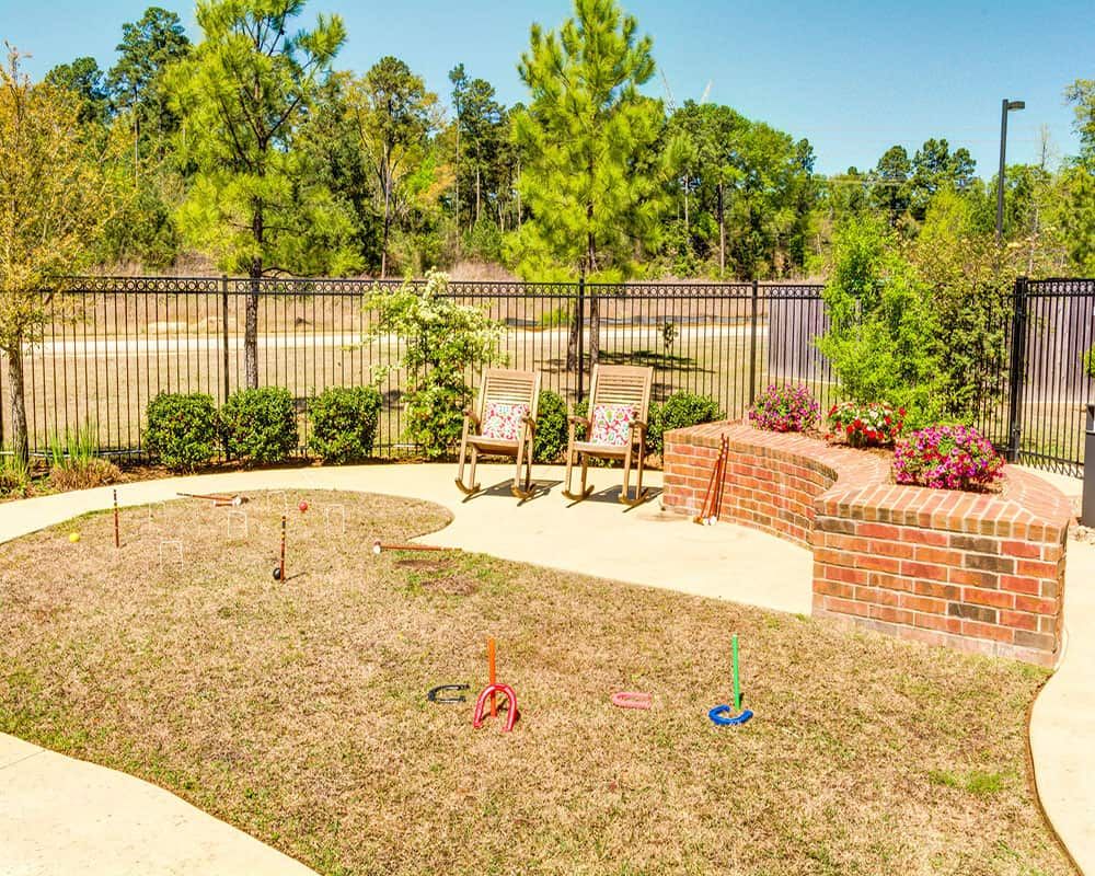 A cozy backyard with a paved path, outdoor chairs, and lush greenery.