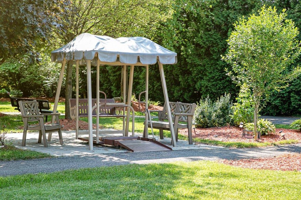 A tranquil garden setting with benches under a shaded canopy swing.