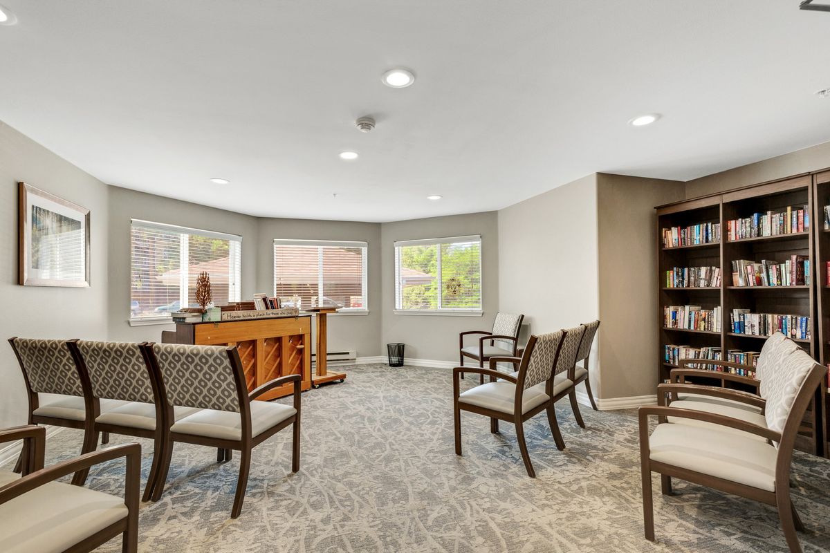 A spacious waiting room with chairs, a desk, and natural light coming through windows.