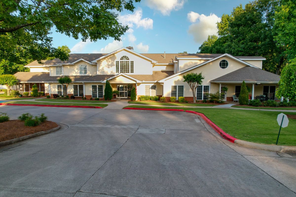 A suburban residential building with a landscaped driveway under a partly cloudy sky.