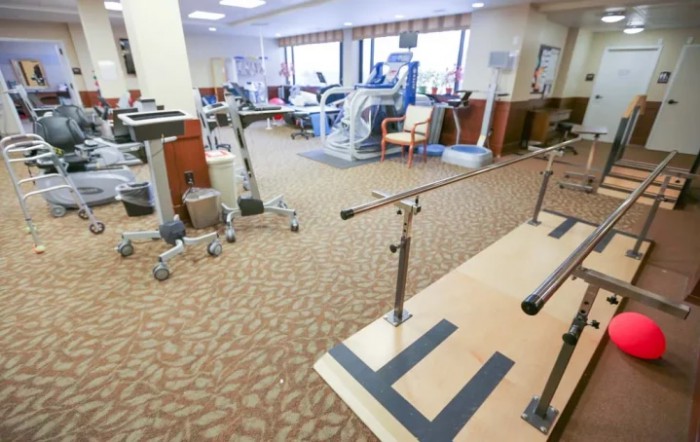 A well-equipped physical therapy and rehabilitation room with exercise machines and parallel bars.