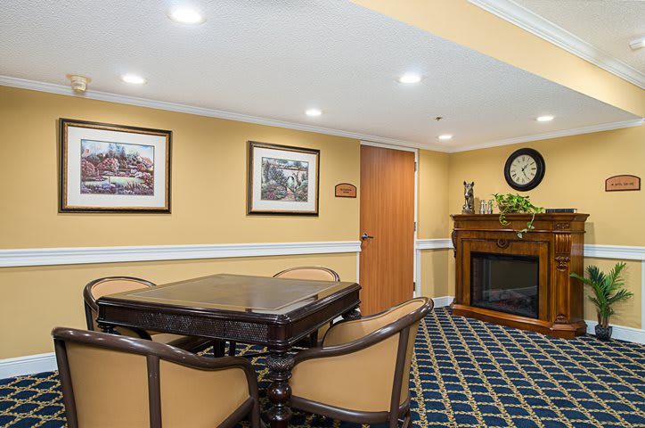 A cozy dining room with elegant decor, featuring a central table, chairs, artwork on the walls, and a fireplace.