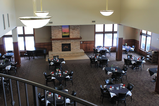 A spacious dining area with elegantly set tables and a cozy fireplace.