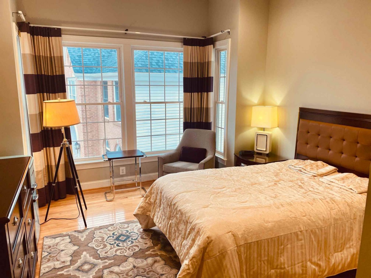 A cozy bedroom with a large bed, stylish lamps, and natural light from big windows.