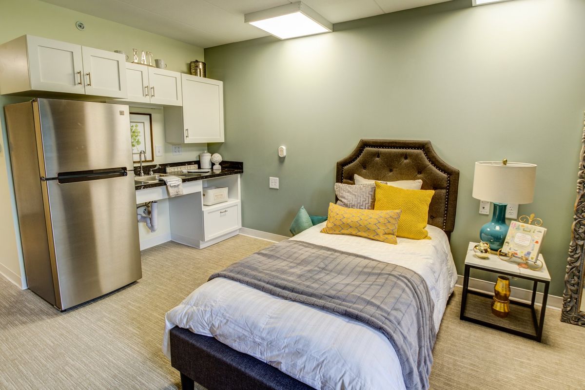 A modern studio apartment with a cozy single bed and a kitchenette.