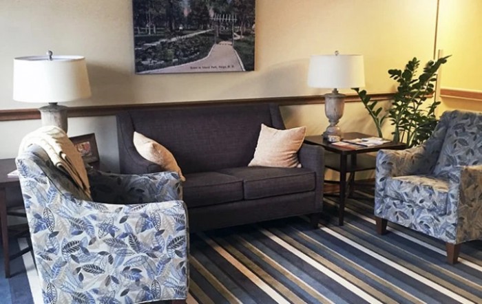 A cozy living room with a sofa, armchairs, and a striped carpet.