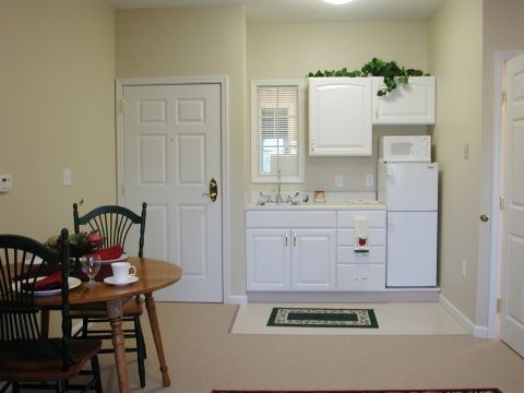 A cozy kitchenette with white cabinets and a small dining table.