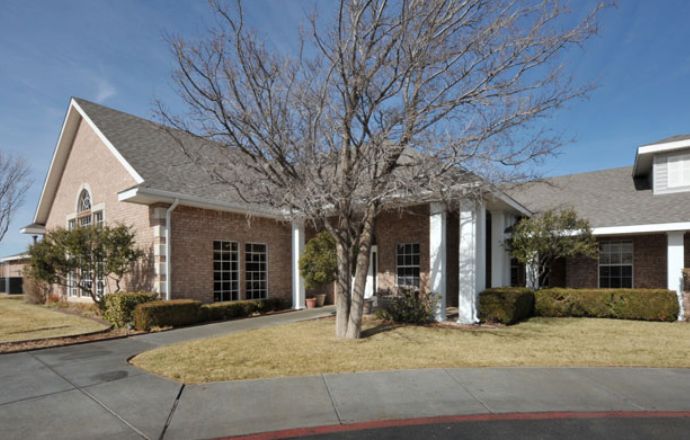 A brick house with white columns and a tree in the front yard.