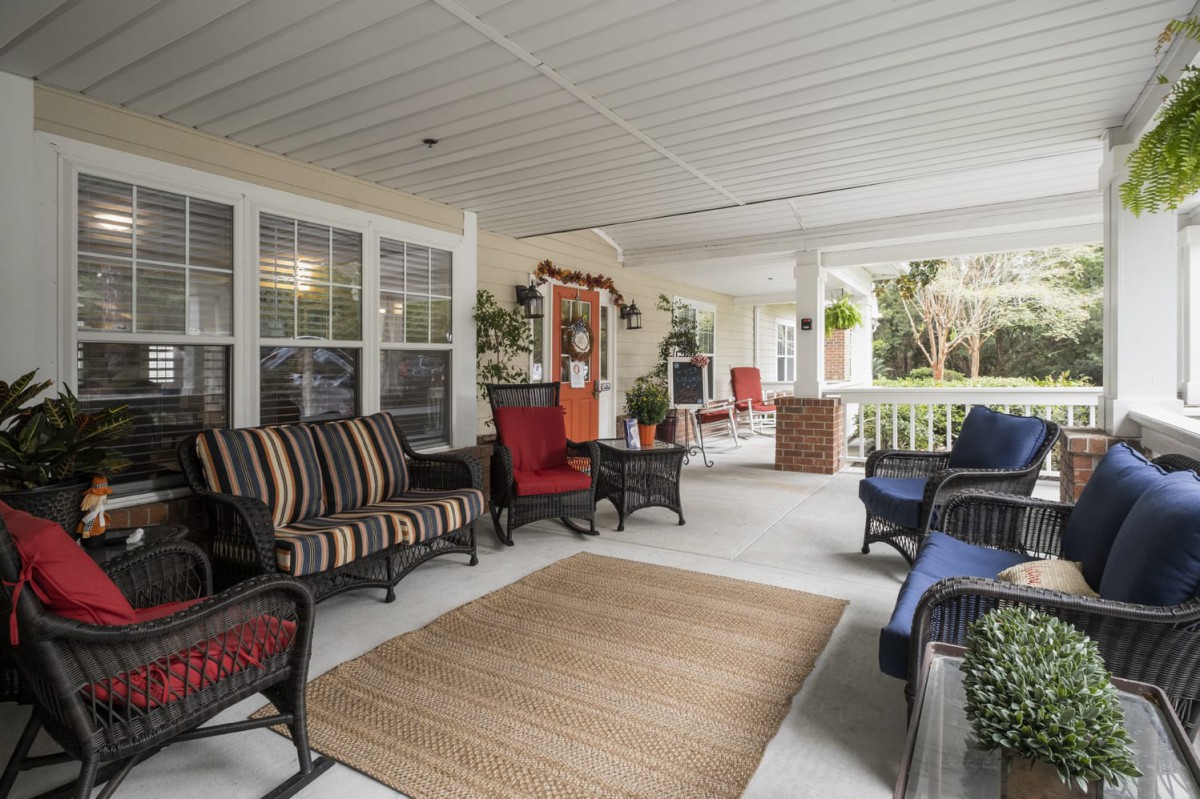 A spacious porch featuring comfortable seating with cushions and a variety of decorations.