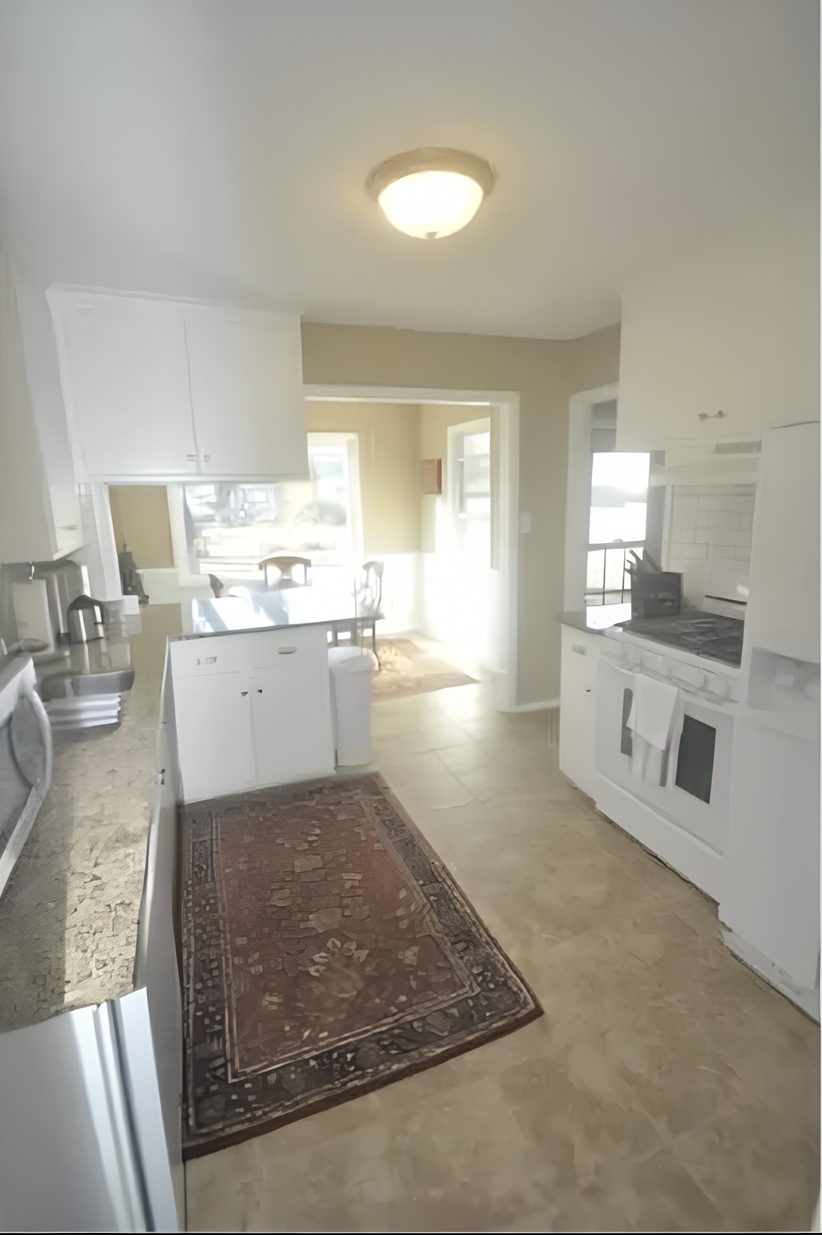 A bright and modern kitchen with white cabinets, granite countertops, and various appliances.