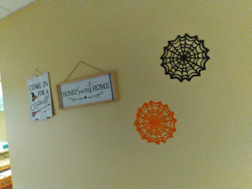 A cozy wall decorated with Halloween-themed spider webs and a cheerful sign.