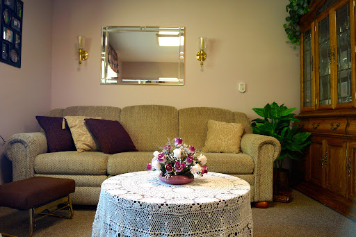 A cozy living room setup featuring a comfortable sofa, decorative table with flowers, and a mirror on the wall.