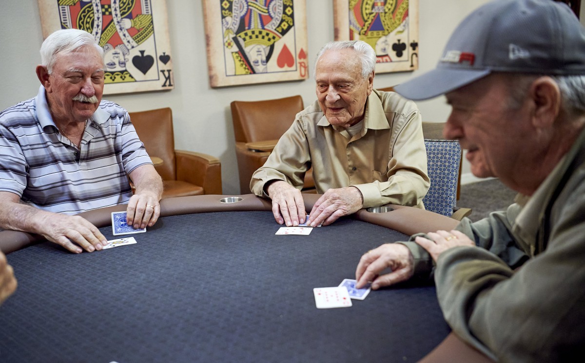 A group of people playing poker at a table indoors.