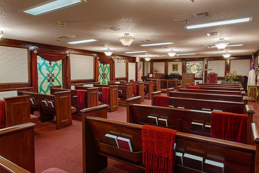 Interior view of a church with wooden pews and stained glass windows.