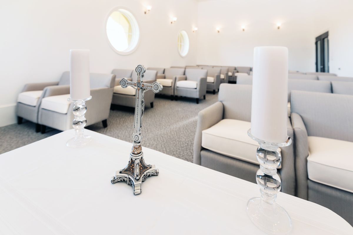 A modern chapel interior featuring seating areas, a decorative cross, and candles.