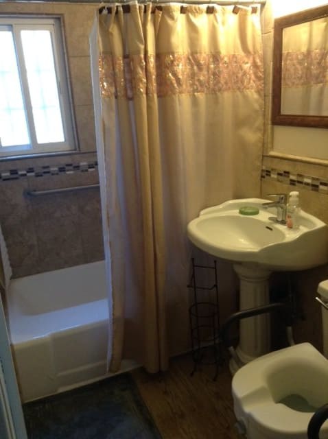 A cozy bathroom with a pedestal sink and a shower area surrounded by a curtain.