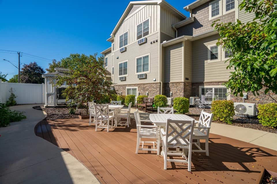 A sunny patio with outdoor seating in front of a residential building.