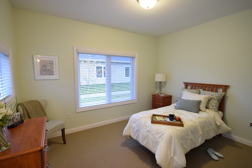 A cozy bedroom featuring a single bed, light green walls, and natural lighting.