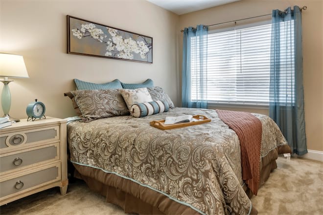 A cozy, well-decorated bedroom featuring a patterned bedspread and a tray on the bed.