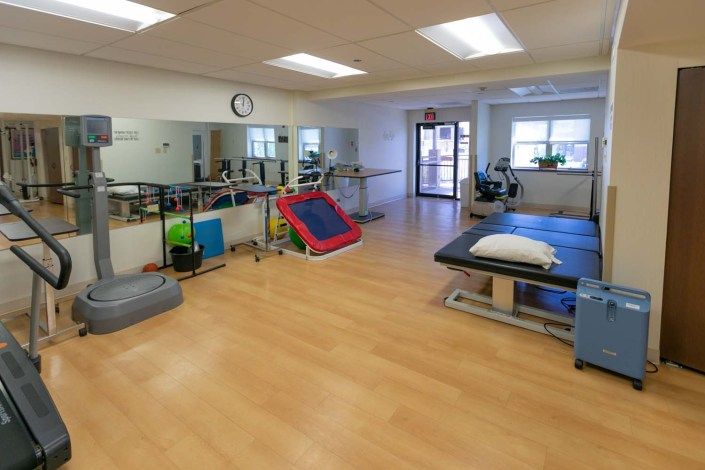 A well-equipped physical therapy room with exercise equipment and treatment tables.