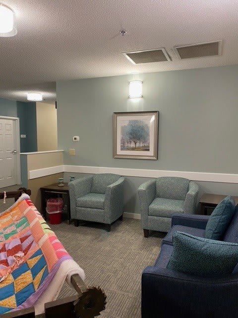 A cozy waiting room with comfortable chairs, a colorful blanket, and wall artwork.