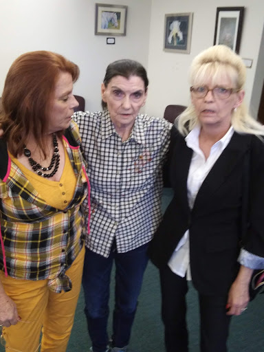 Three women posing together in a friendly setting.