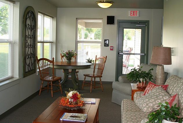 A cozy living room with a table, chairs, and a sofa adorned with plants and decor.