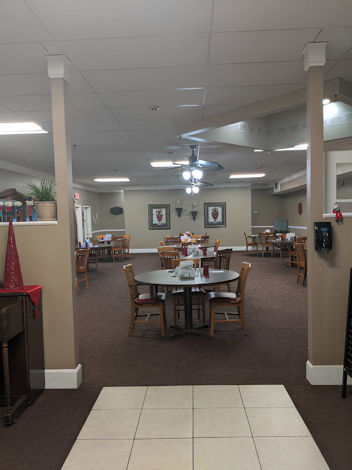 A cozy dining room with several tables and chairs arranged neatly under ceiling fans.