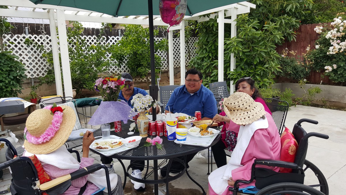 A group of people enjoying a meal together outdoors under an umbrella.