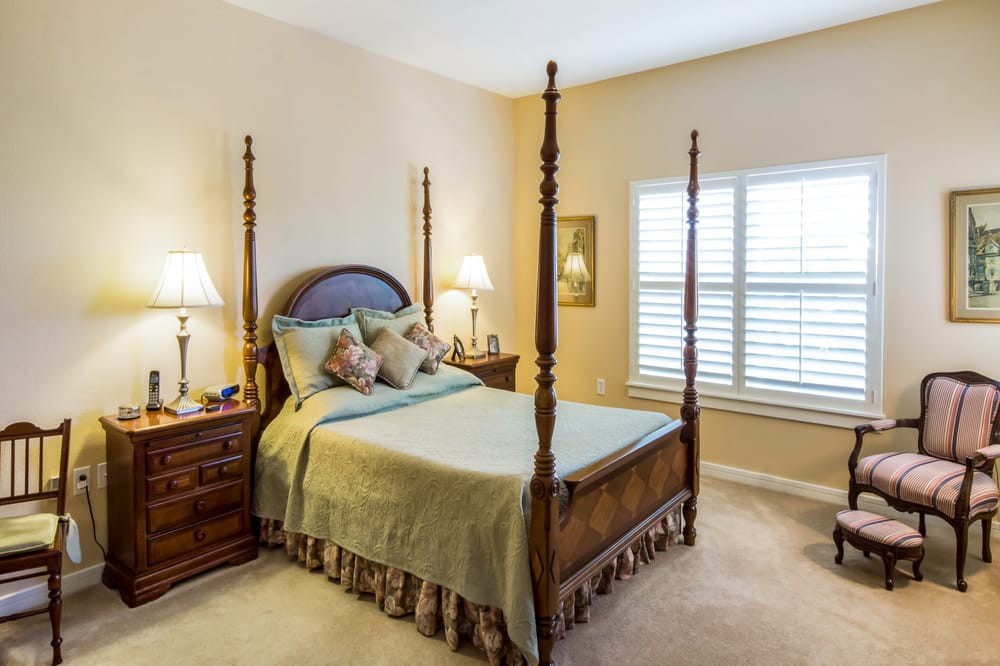 A cozy bedroom with a four-poster bed, nightstands, and lamps.