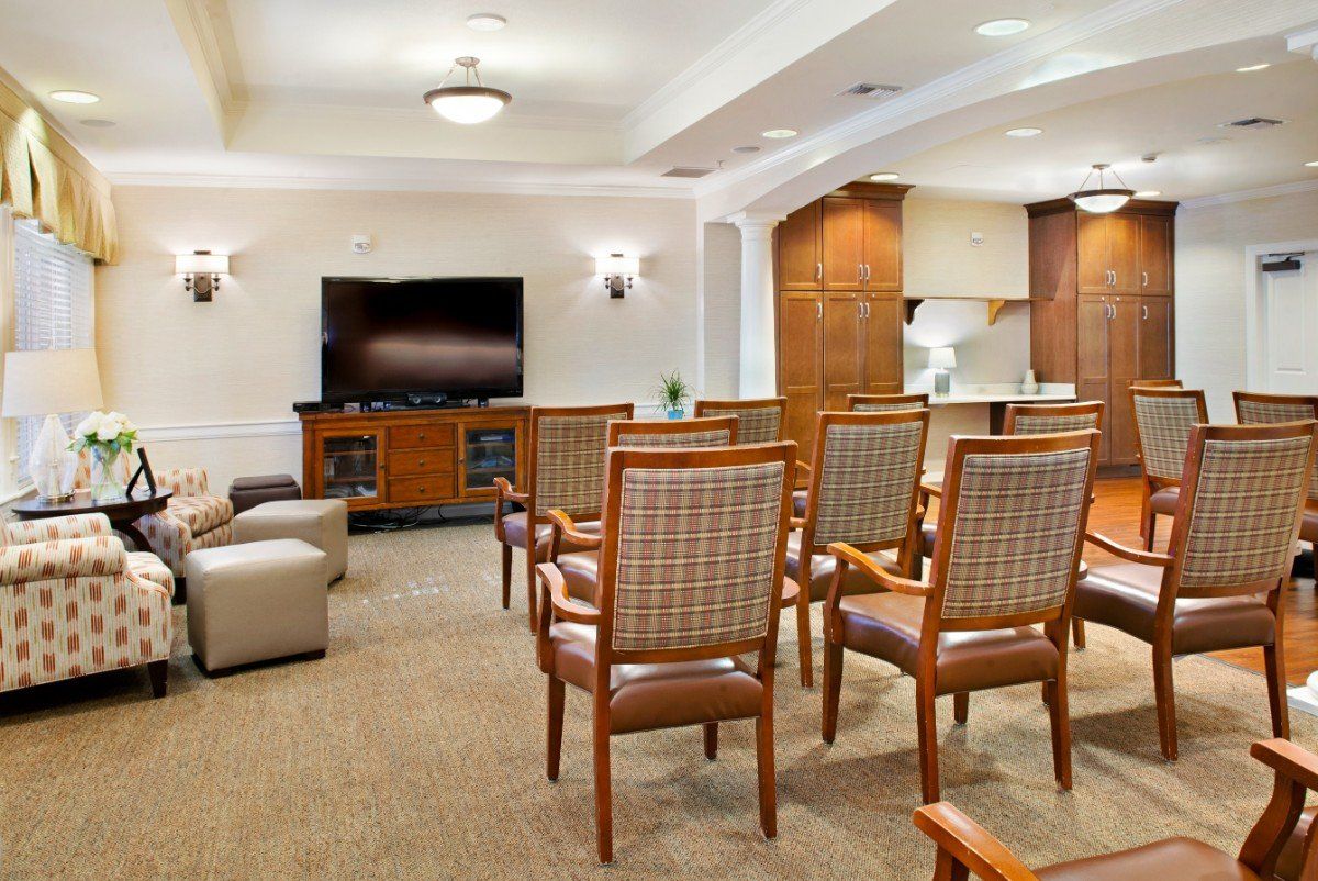 A cozy seating area with wooden chairs arranged facing a television in a warmly decorated living room.