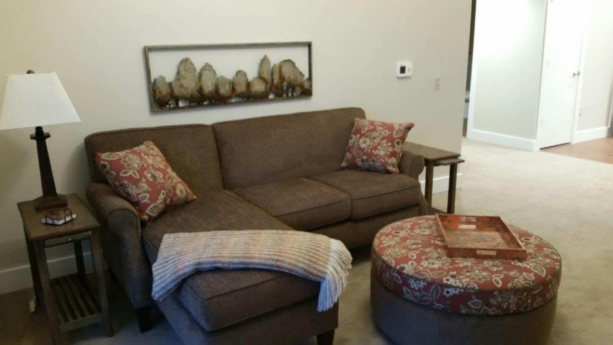 A cozy living room with a brown sectional sofa, decorative pillows, and a round coffee table.