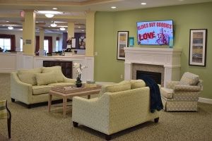 A cozy living room with sofas, a fireplace, and a television displaying a movie poster.