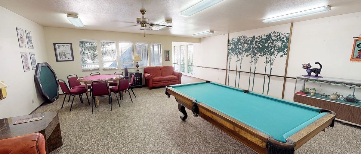 A spacious game room featuring a pool table, seating area, and large windows.
