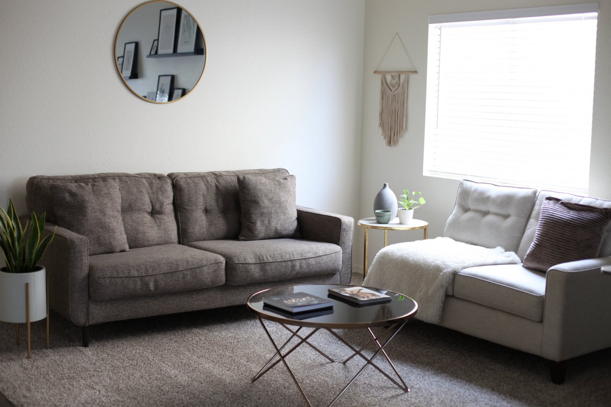 A modern minimalist living room with a gray sofa, round coffee table, and wall decor.