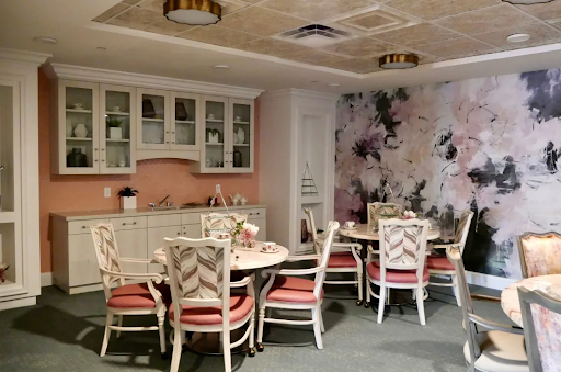 A beautifully decorated dining area featuring a kitchenette, floral wallpaper, and elegant furniture.
