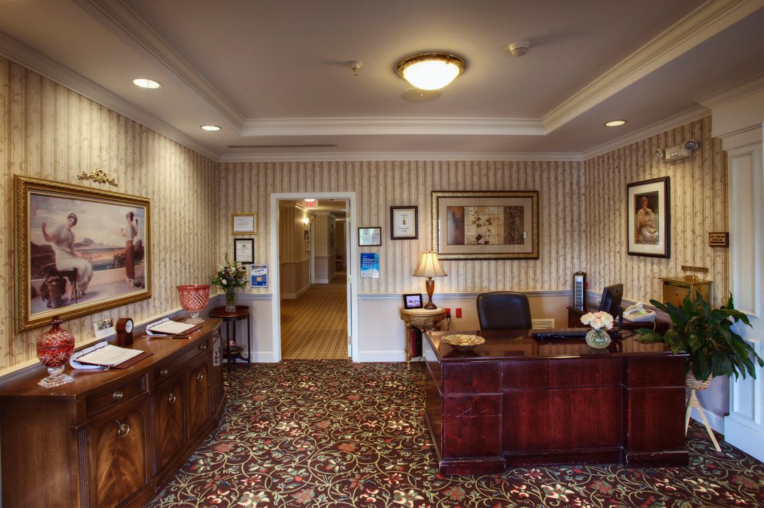 A neatly organized office space with a wooden desk, decorative carpet, and framed art on the walls.