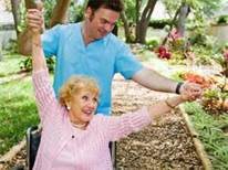 A caregiver assists a joyful senior woman in a wheelchair, enjoying the outdoors in a garden setting.