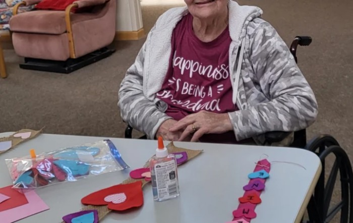 An elderly person engaging in crafting activities, creating heart decorations at a table.