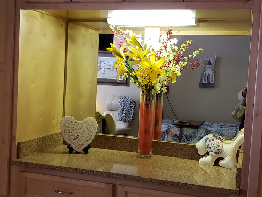 A beautifully arranged vase of yellow flowers sits on a countertop, complemented by a heart-shaped decoration and soft lighting.