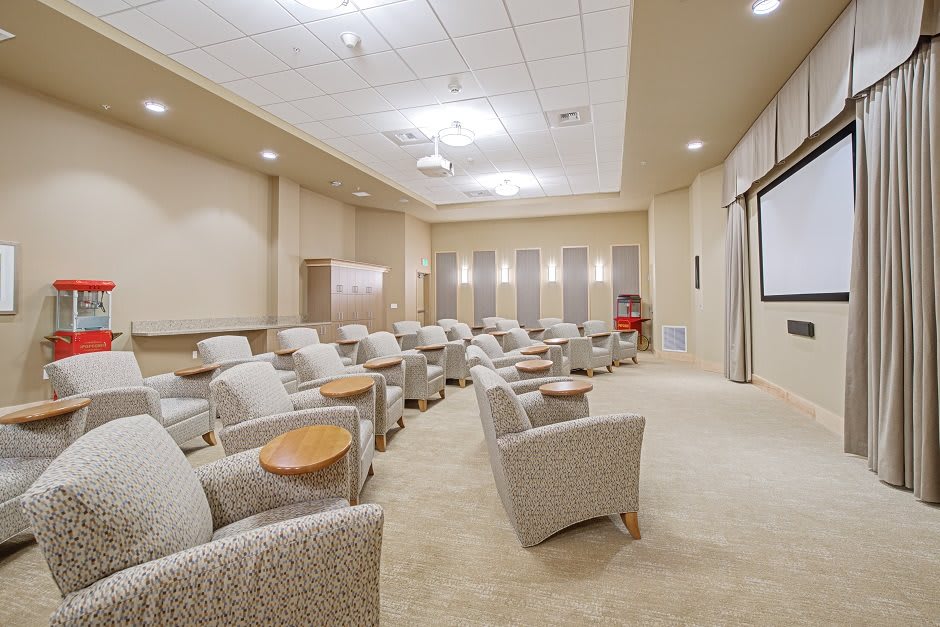 A modern conference room with comfortable seating and a projector screen.
