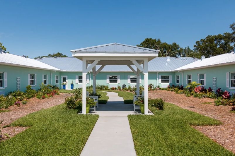 A single-story building with a manicured lawn and clear blue sky.