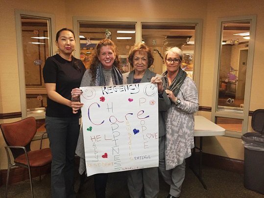 A group of women holding a decorated poster indoors.