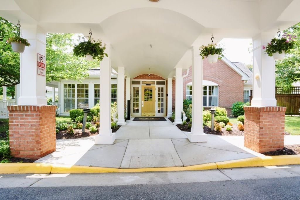 A welcoming entrance to a building with landscaped surroundings and decorative columns.