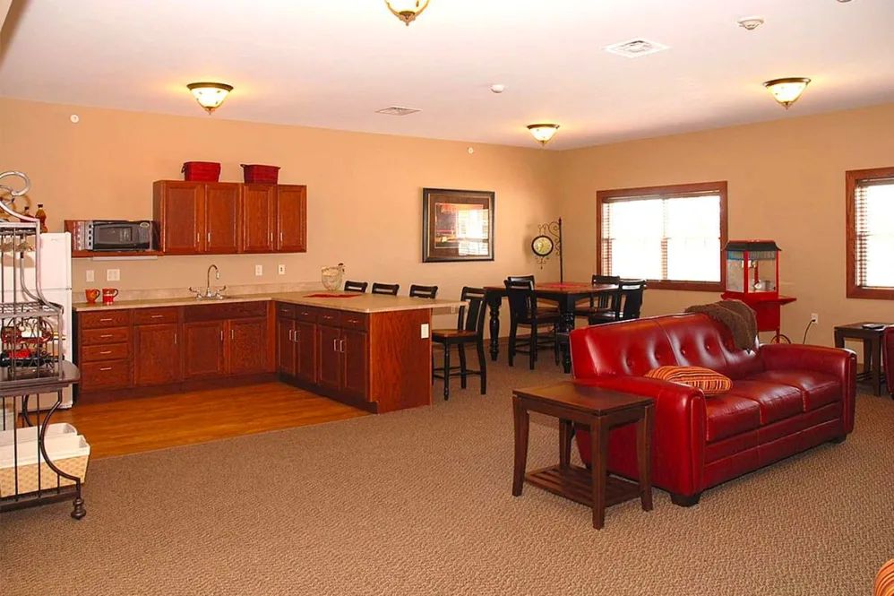 An open-concept living space featuring a kitchen and dining area with modern furnishings, including a red sofa.
