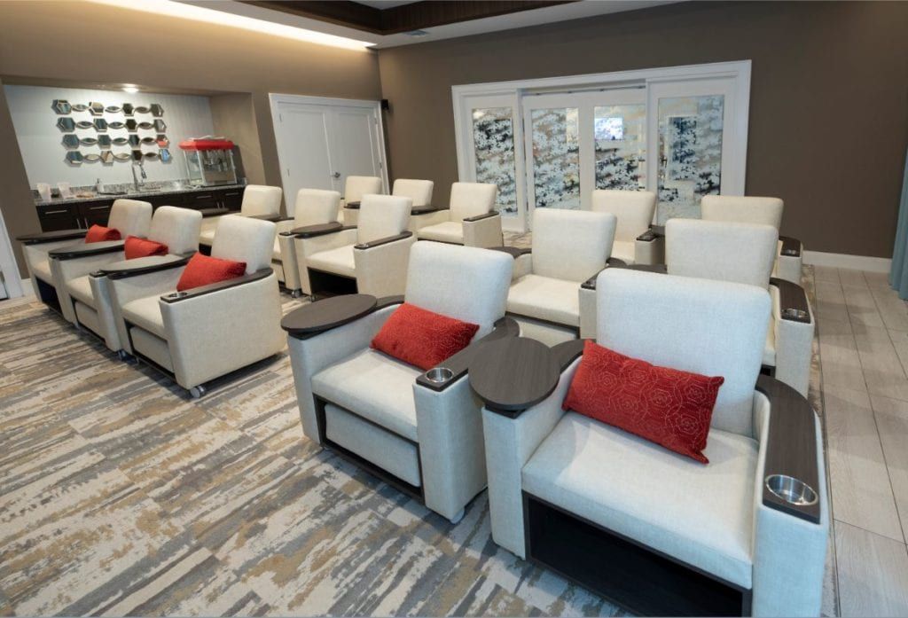 A luxurious home theater room with comfortable recliner chairs and red accent pillows.