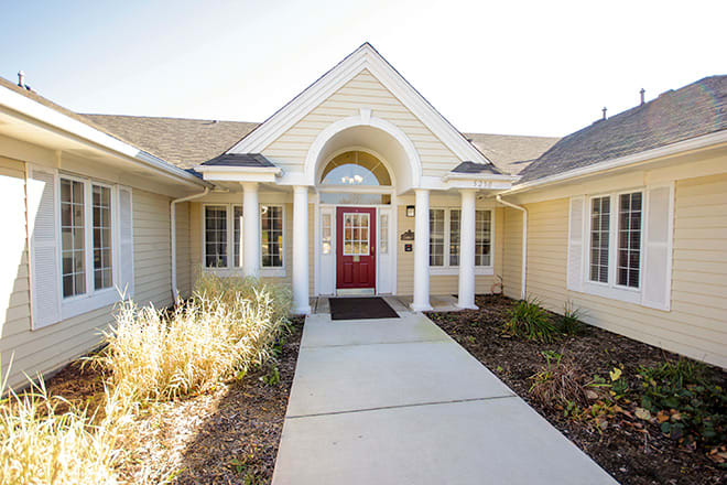 A welcoming house entrance featuring a red door and white columns.