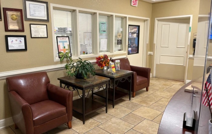 A cozy waiting room with comfortable chairs and a table adorned with plants and magazines.