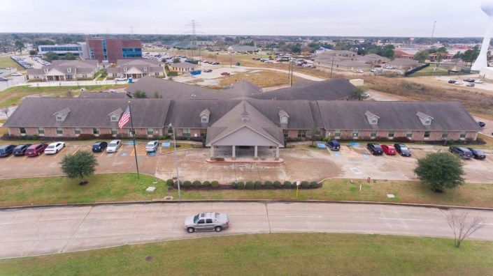 Aerial view of a suburban building with a parking lot and surrounding area.